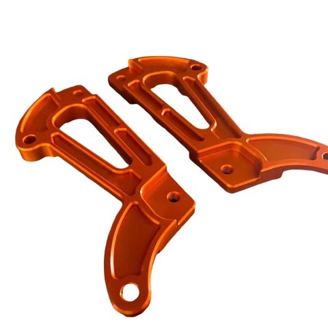 Dvi oranžinės spalvos anoduoto aliuminio detalės, skirtos elektrinio motociklo rėmo stiprinimui ar apdailai.
